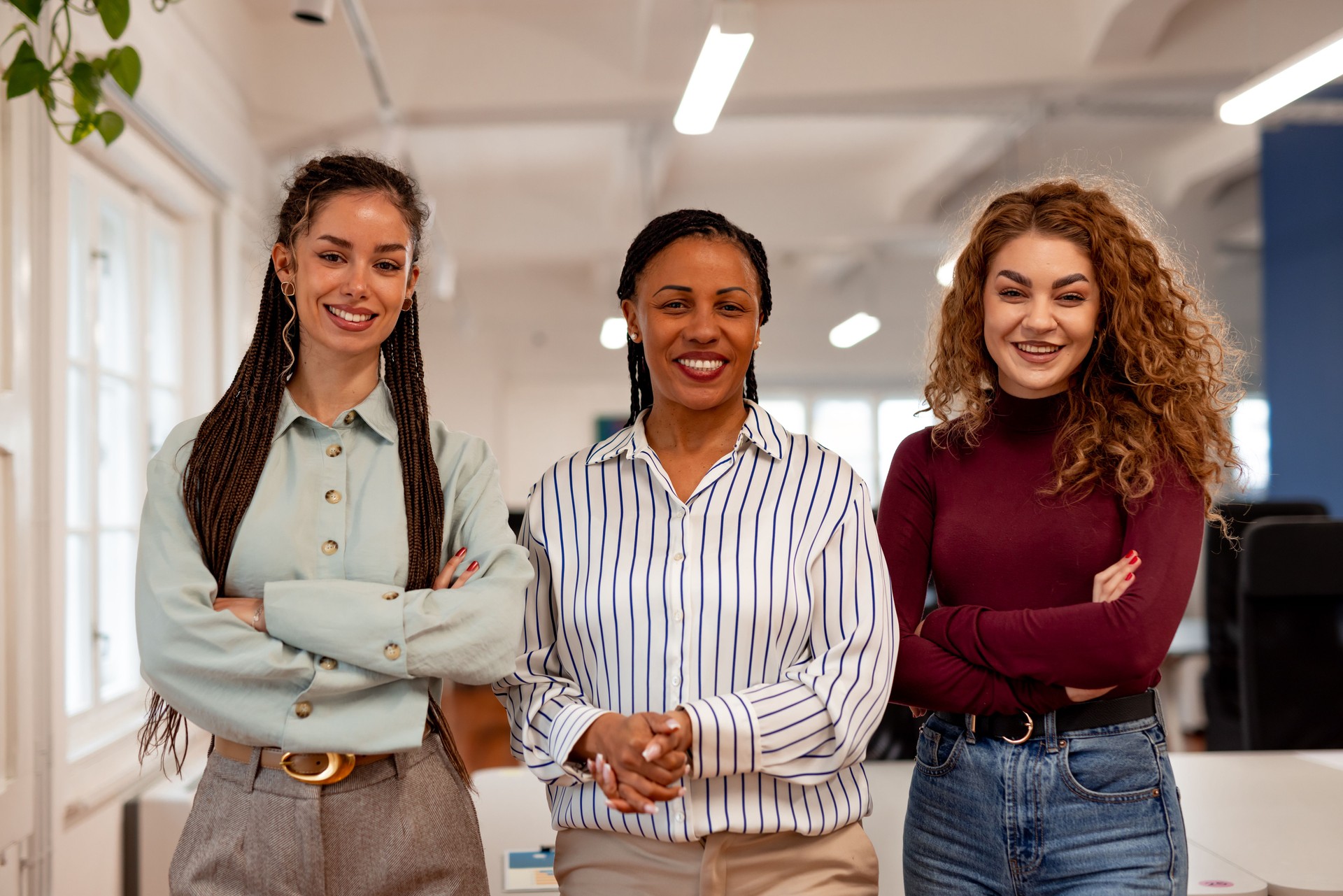 Confident Team of Three Women Smiling in a Bright Workspace