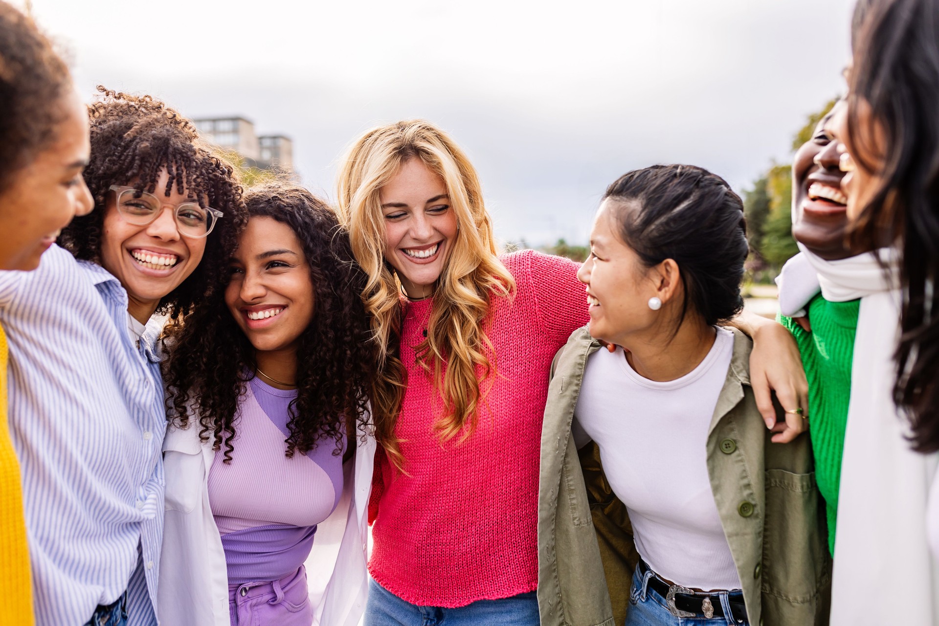 Young group of diverse happy girls laughing together at city street